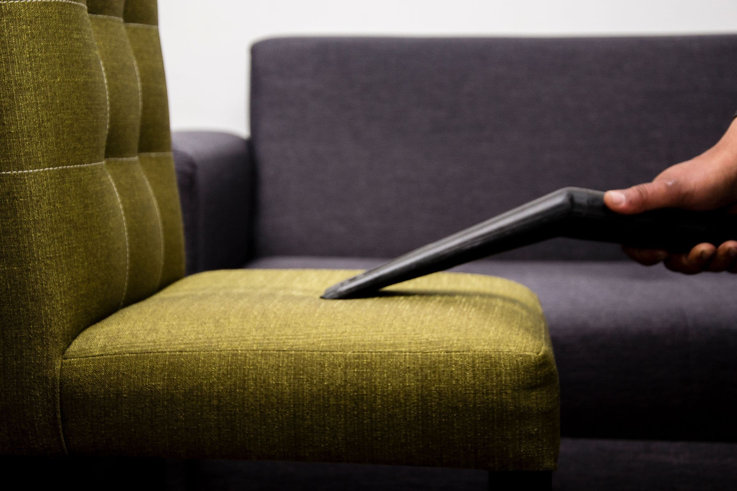 A technician cleaning an upholstered chair with an extraction tool